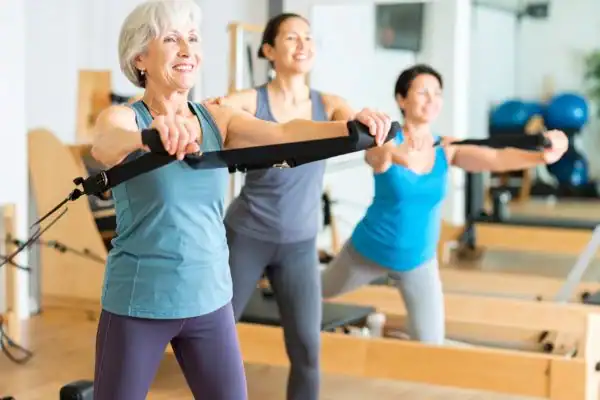 Toning Arms After 60: Empowering Womens Fitness Through Effective Weight Training 2 older woman doing weight training West Malling and resistance in the gym to tone upper arms